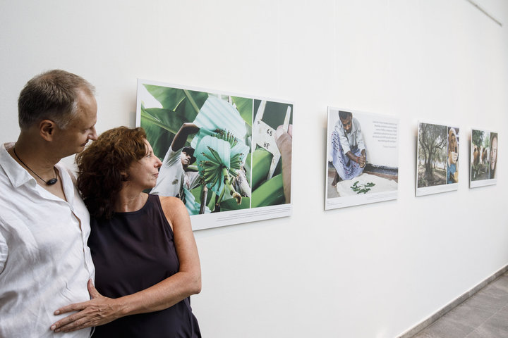  Zwei Personen schauen sich Fotos einer Ausstellung an, die an einer weißen Wand hängen